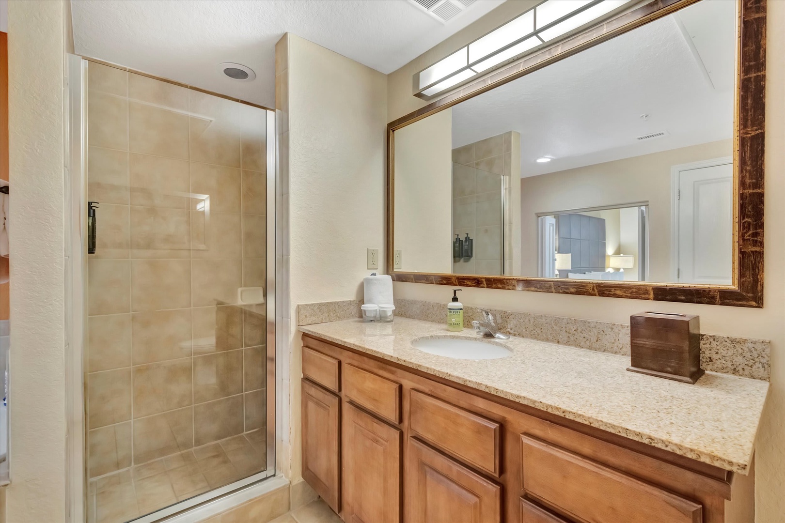 Freshen up in your spacious bathroom with a walk-in shower, granite countertops, and warm wood cabinetry for a comfortable start to your day.