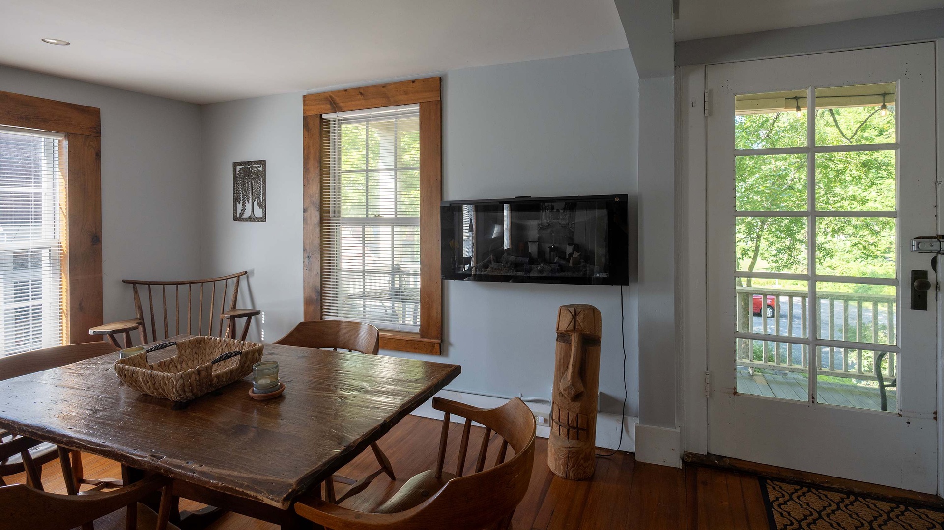 Warm sunlight filters through the windows, illuminating your dining space with rustic wood furnishings and doors opening to a private balcony overlooking lush greenery—your perfect spot for morning coffee or evening relaxation.