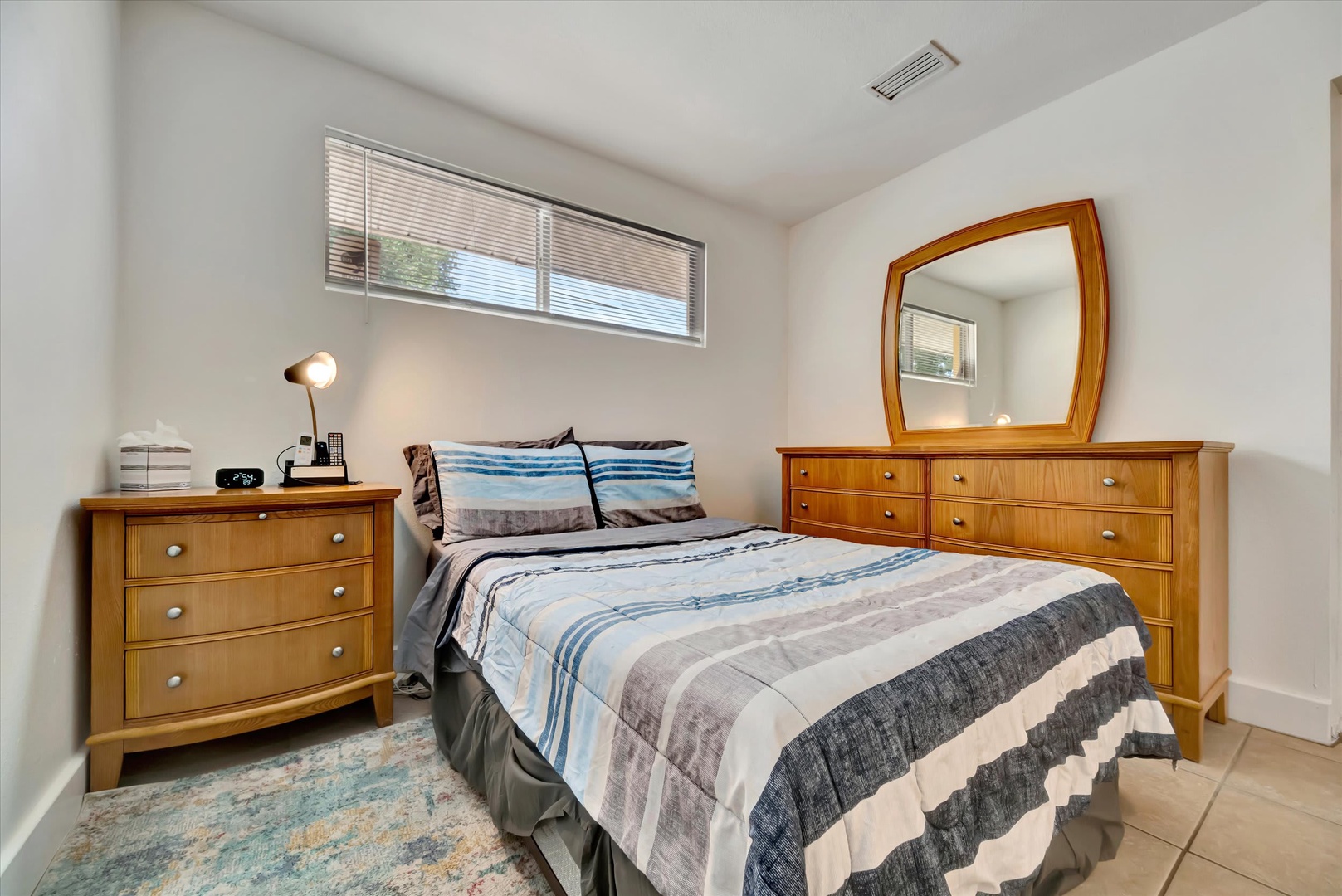 Step into your tranquil bedroom, where clean lines and warm wood tones create a calming retreat. Natural light filters through the window above your bed, and the soft bedding invites you to unwind after exploring the area.