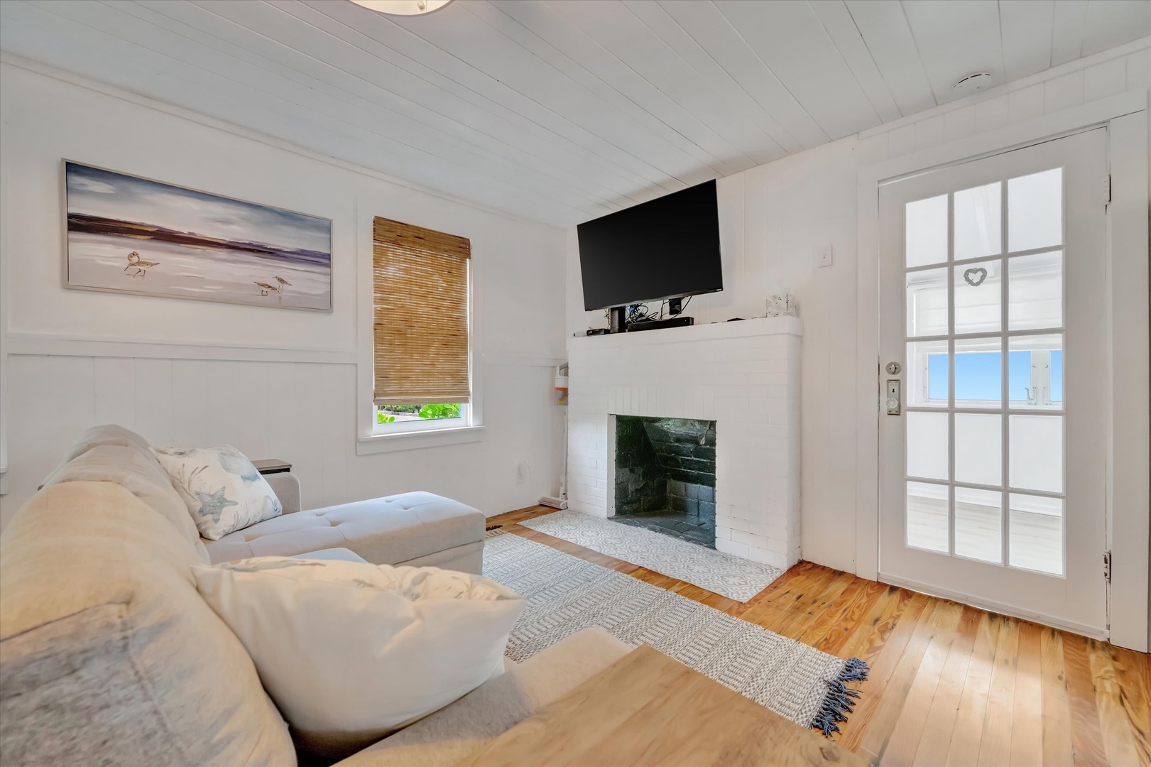 Sink into the plush sofa and let the coastal charm embrace you. The fireplace adds warmth while ocean breezes drift through the door, creating your perfect retreat.