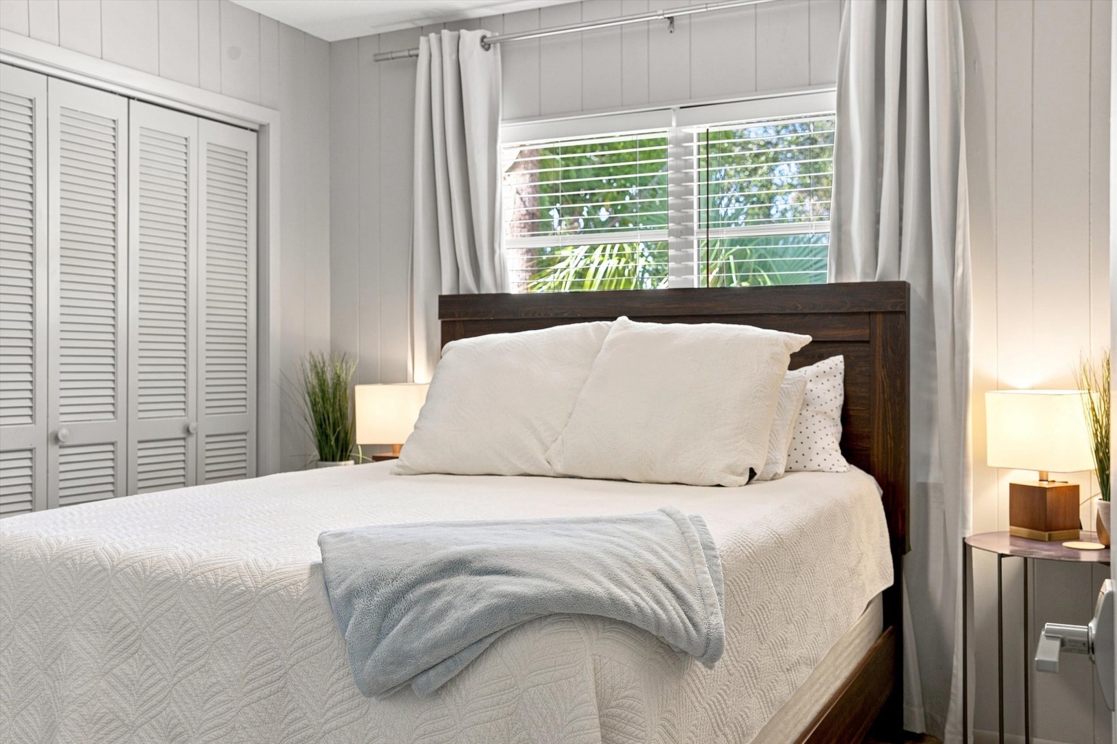 Sink into your plush bed with crisp linens and soft throw while natural light filters through the window—your peaceful retreat after a day of exploring.