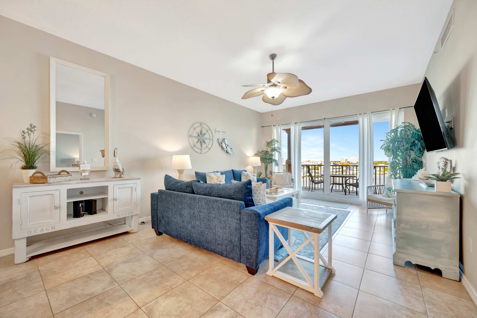 Sink into plush blue sofas and feel the coastal breeze drift through your private balcony doors. This bright, airy living room invites you to unwind with thoughtful touches like soft lighting and beach-inspired décor.
