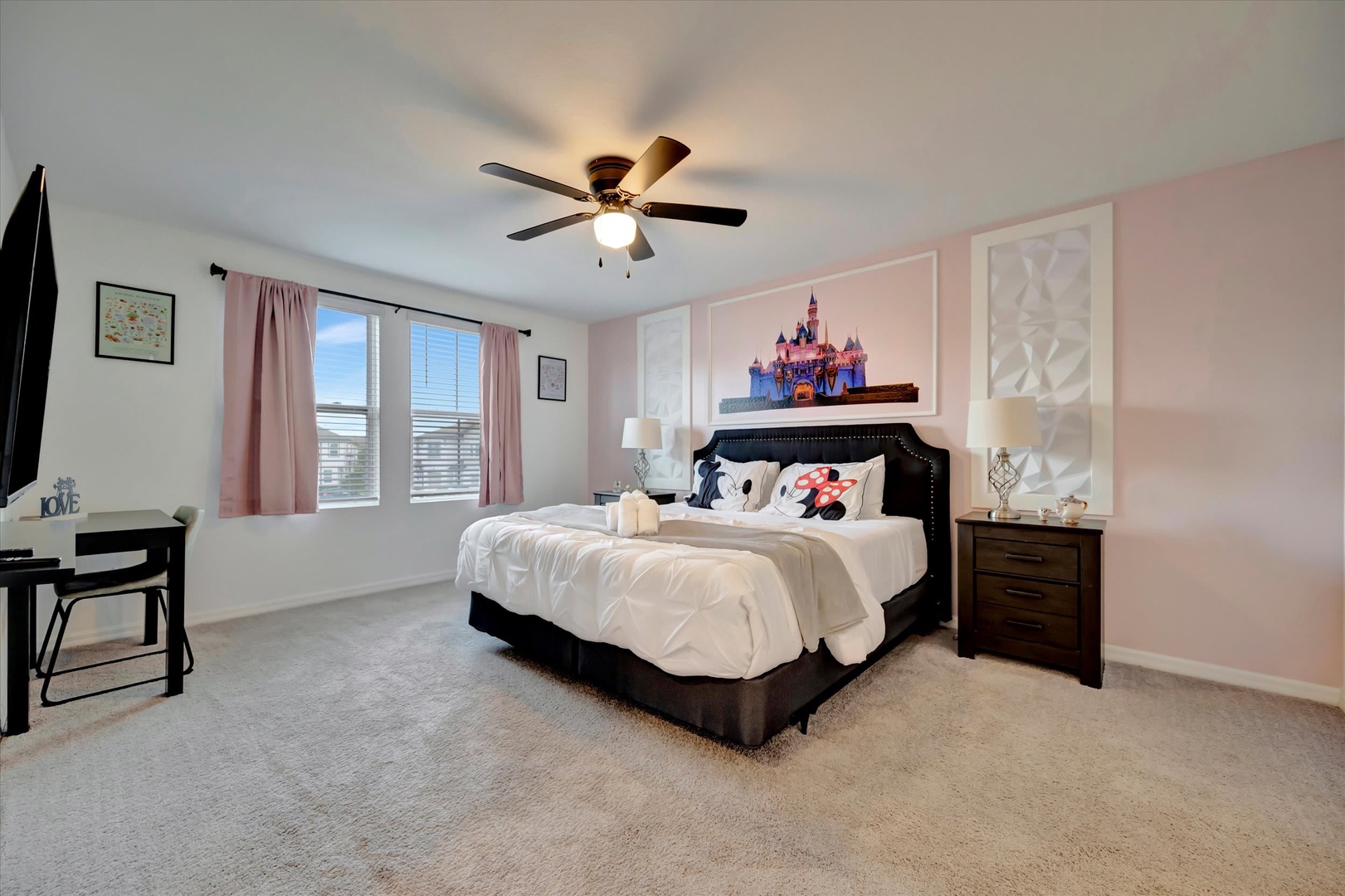 Rest easy in your spacious bedroom with plush bedding, gentle ceiling fan, and soft natural light from bright windows creating a peaceful retreat for relaxation.