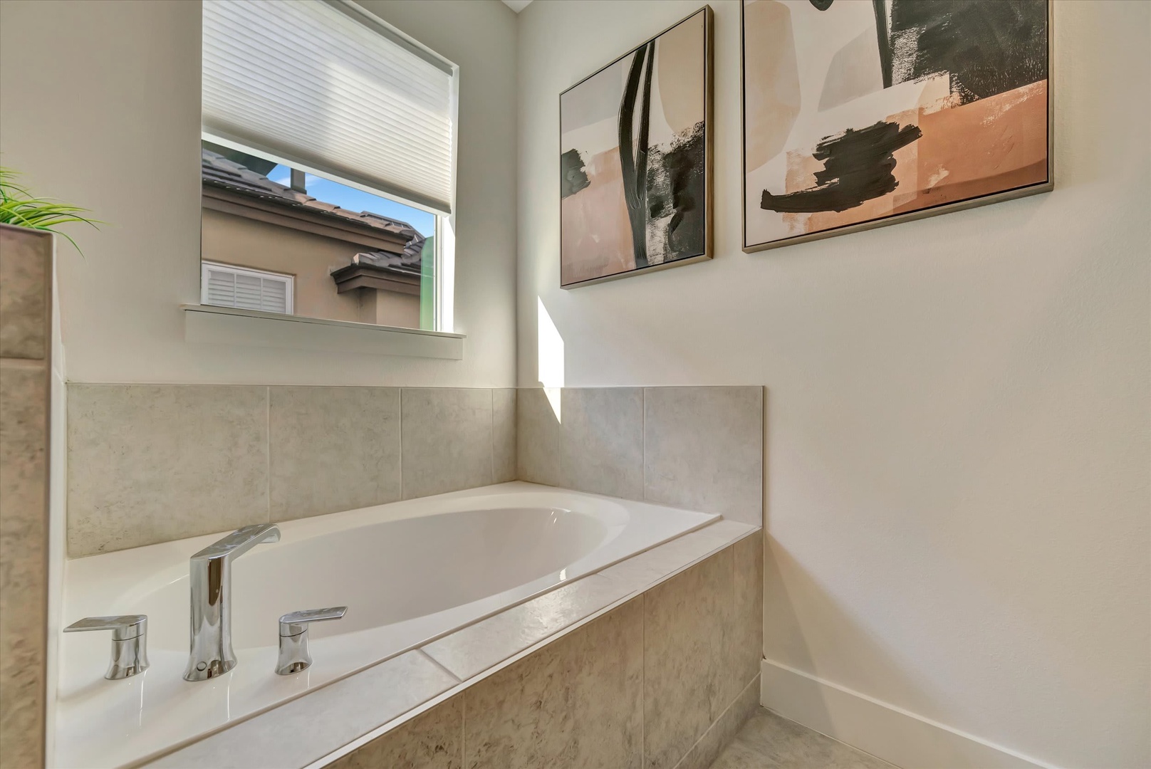 Unwind in your serene soaking tub, where soft natural light and elegant artwork create a spa-like retreat perfect for relaxation after exploring the area.