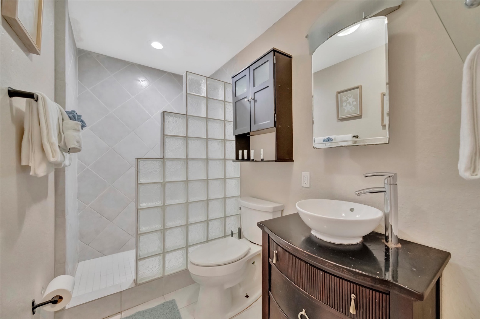 Refresh in your private bathroom, featuring a walk-in shower, modern vessel sink, and fresh towels waiting for you after a long day of exploring.