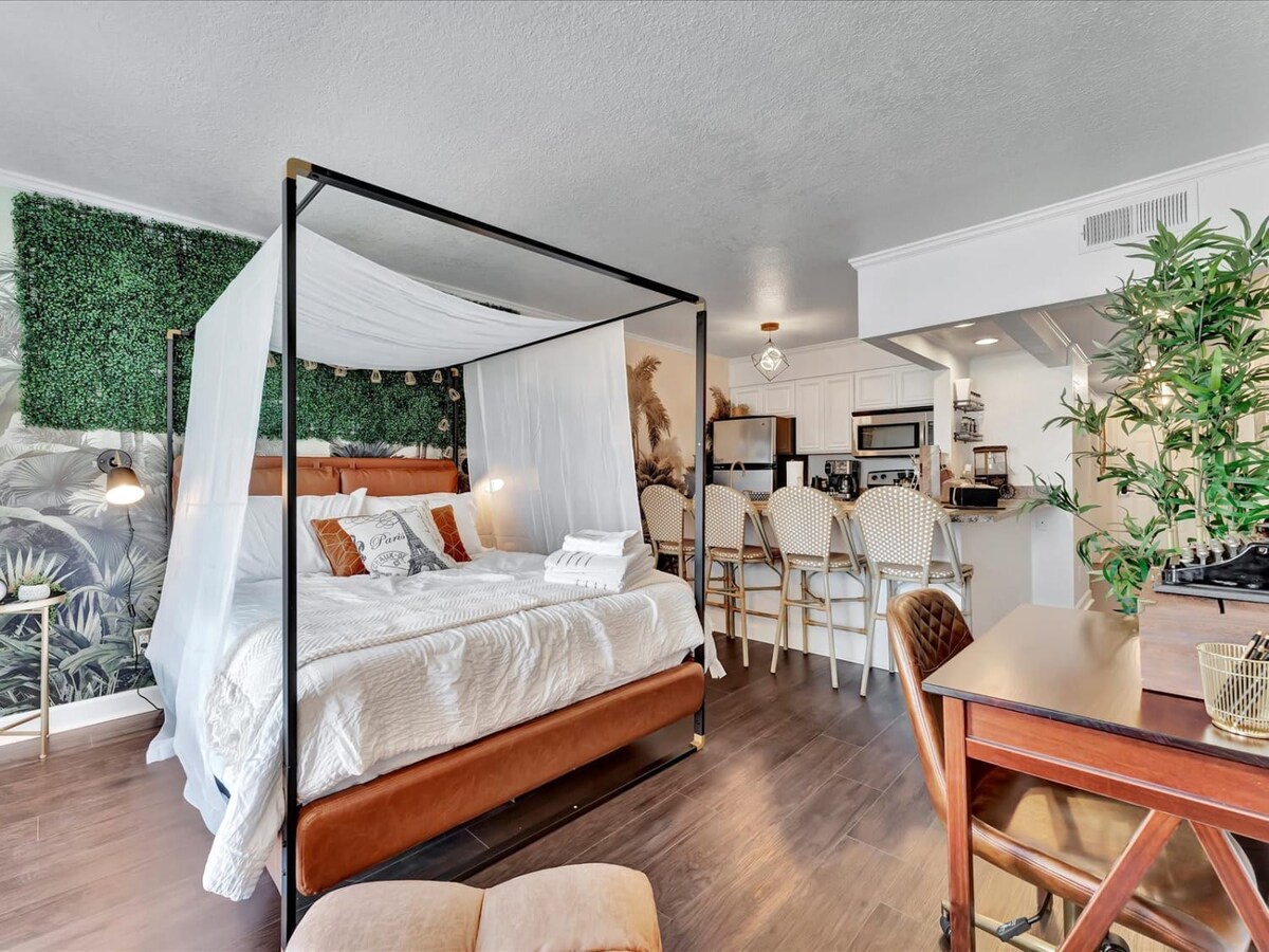 Drift off in your elegant canopy bed, surrounded by soft linens and tropical touches. Your open kitchen awaits for morning coffee, while lush greenery and stylish seating create a serene, boutique retreat.