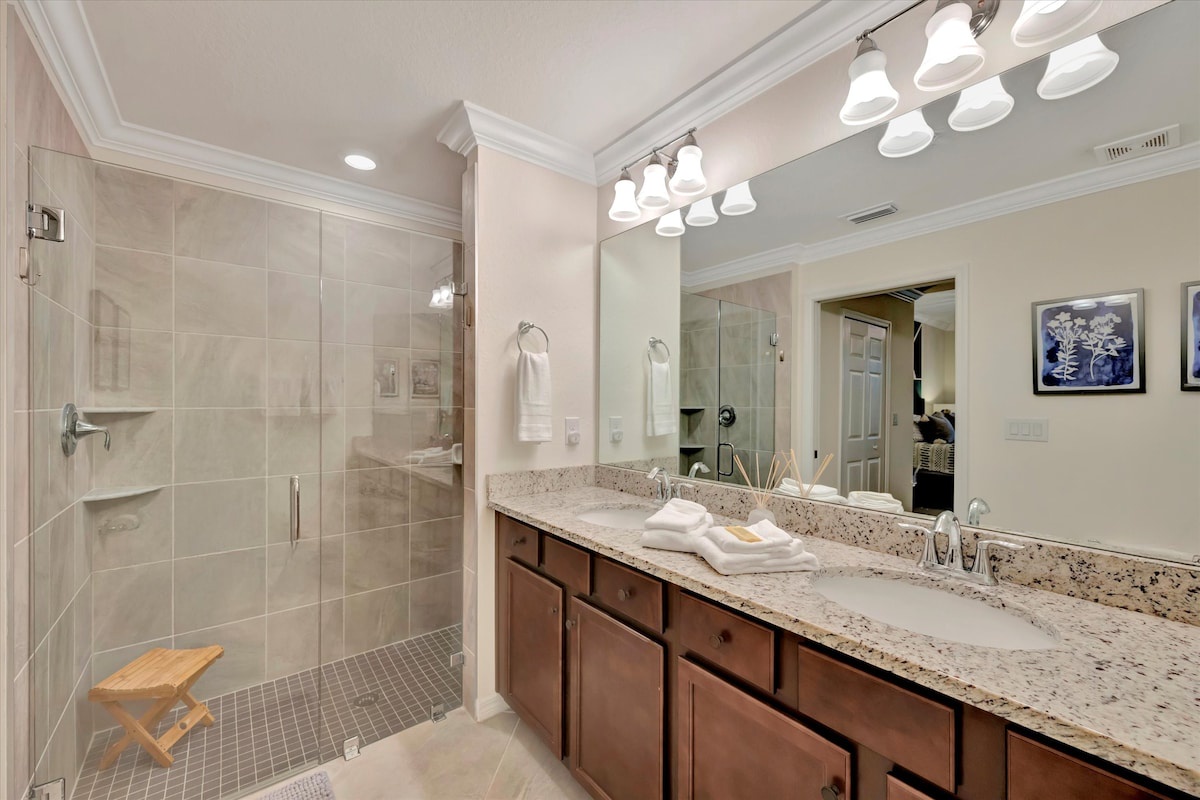 Step into your serene private bathroom, where soft natural tones and elegant granite meet a spacious walk-in shower. Fresh towels await, inviting you to unwind in comfort.