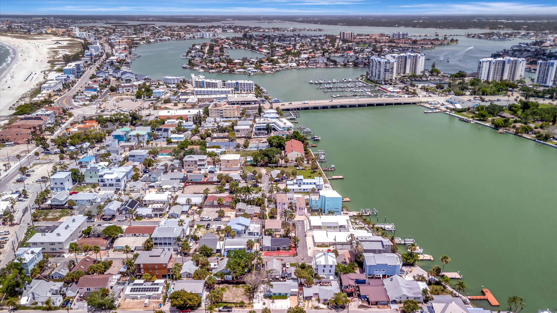 Aerial view of a coastal beach community with waterfront homes, bridges, and nearby sandy shores.