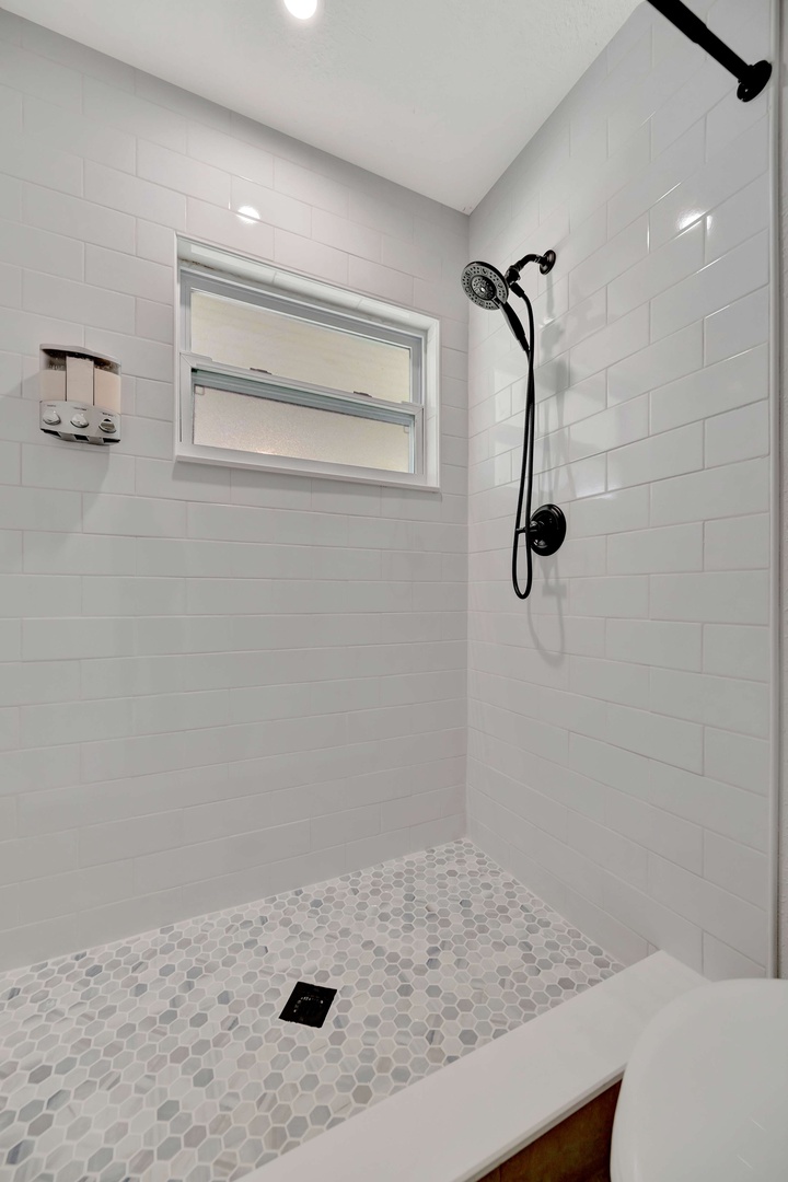 Step into your private retreat—a bright, spacious shower with gleaming subway tiles and rainfall showerhead, ready to refresh you after a day of adventure.