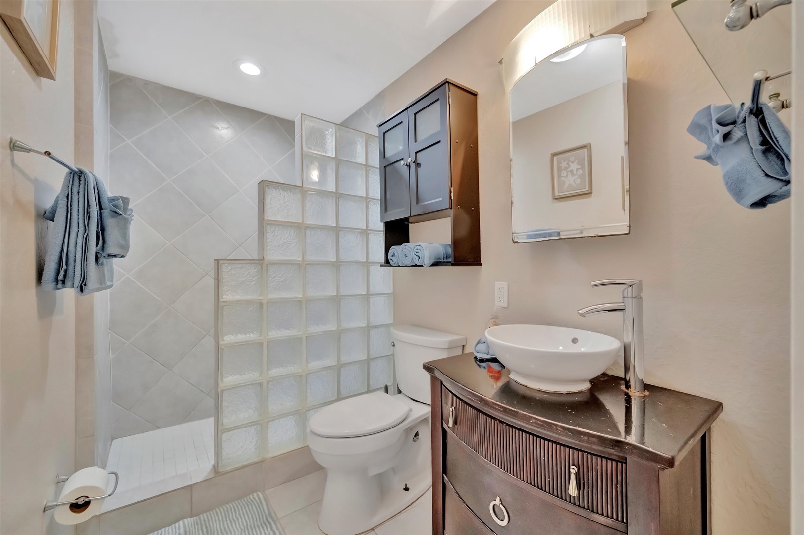 Refresh after your adventures in this thoughtfully designed bathroom, featuring a glass-block shower, vessel sink, and elegant finishes that bring modern comfort to your coastal retreat.