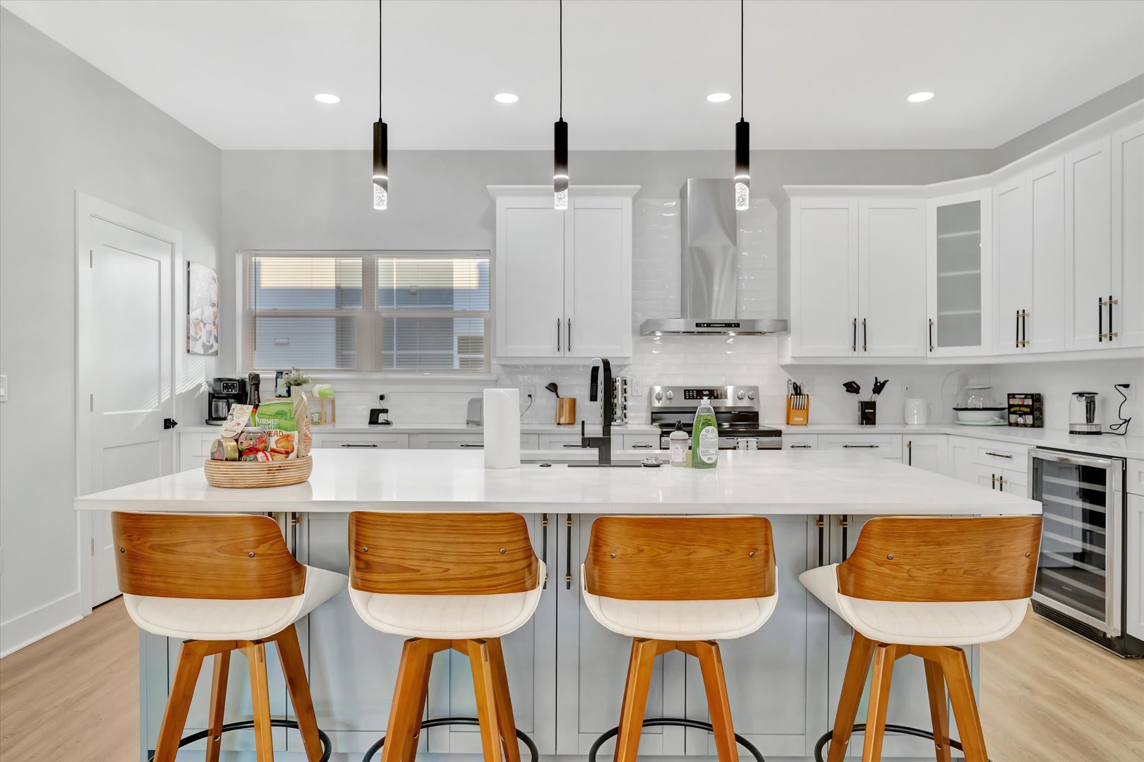 Picture yourself preparing meals in this bright, modern kitchen with sleek white cabinetry, spacious countertops, and a convenient island—your perfect gathering spot for morning coffee or evening conversation.