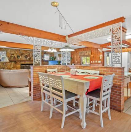 Step into your open-concept dining and kitchen area with warm wood beams and a welcoming brick bar that brings rustic charm to the heart of your vacation home.