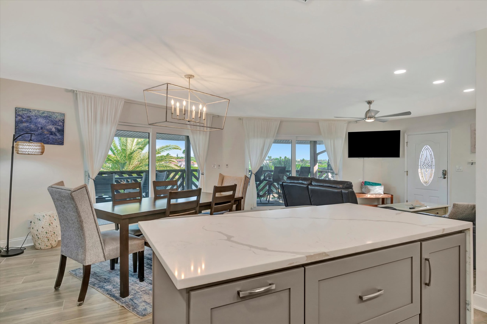 Sun-filled open-concept living with coastal views and palm trees. Sleek kitchen island flows into the dining area and private balcony—perfect for morning coffee or evening sunsets.