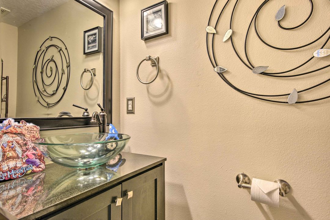 Step into your stylish half-bath with its modern glass vessel sink and artistic spiral wall décor that creates a welcoming, contemporary atmosphere.