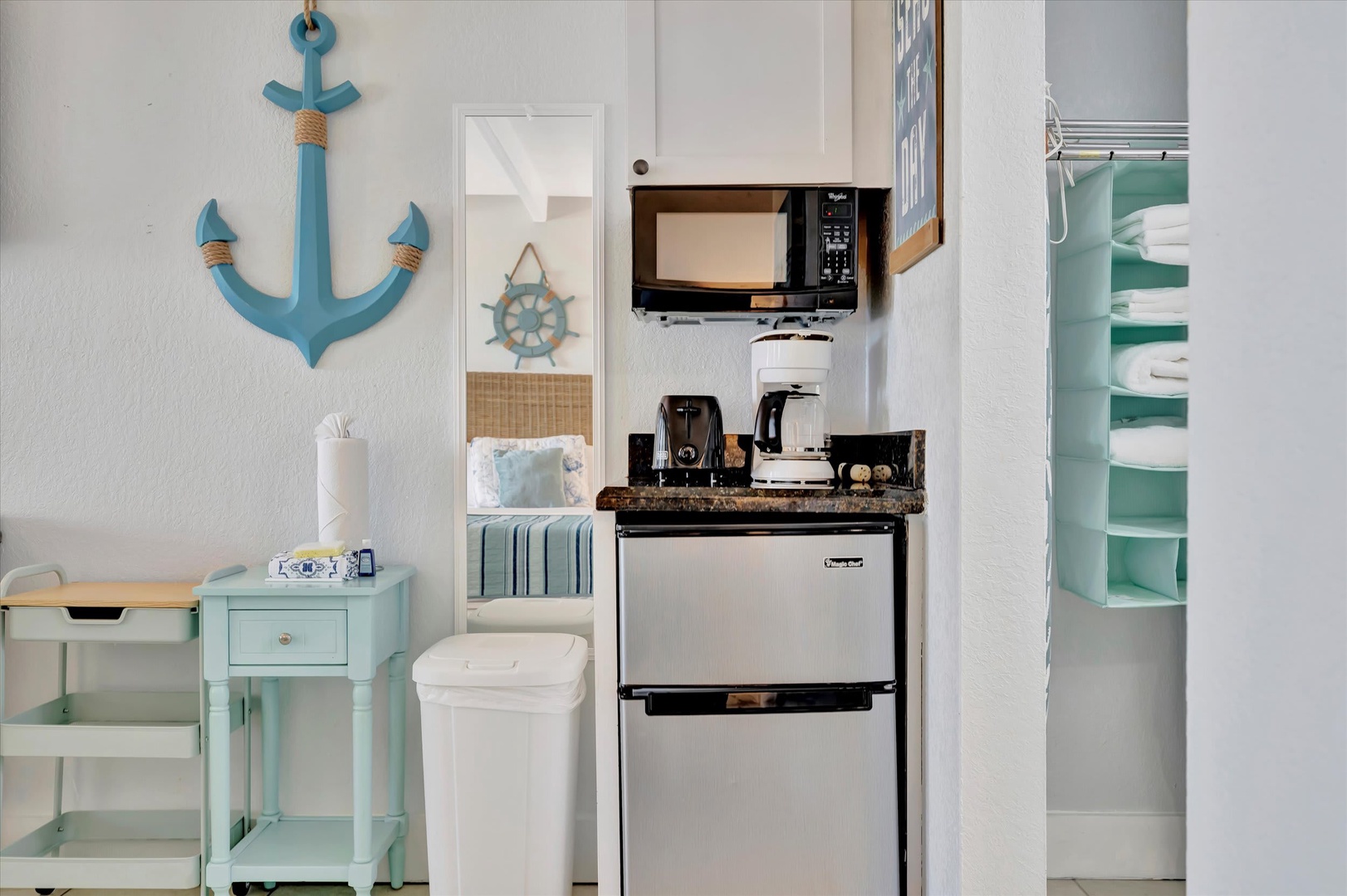 Your coastal-themed kitchenette offers everything you need—a compact fridge, microwave, coffee maker, and convenient storage—all styled with charming nautical touches to set the tone for a relaxing beach getaway.
