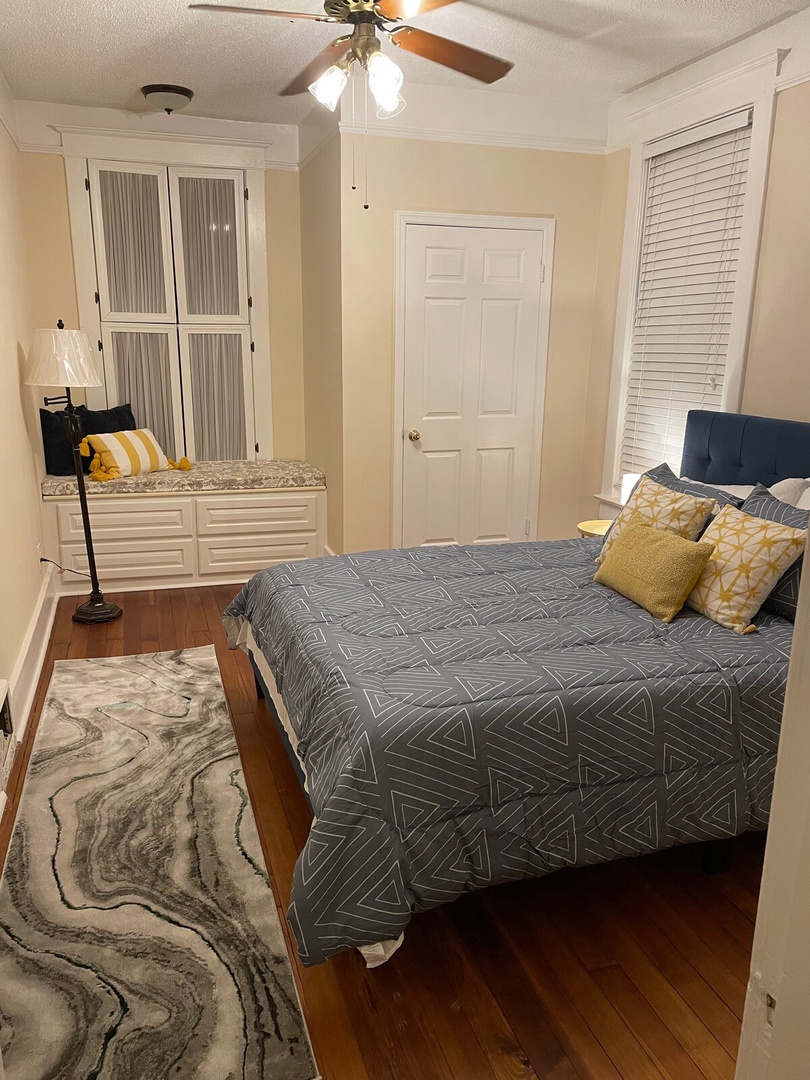 Unwind in your cozy bedroom with warm hardwood floors, stylish built-in storage, and a plush bed ready for restful nights. Bright pops of yellow add a cheerful touch to this inviting retreat.