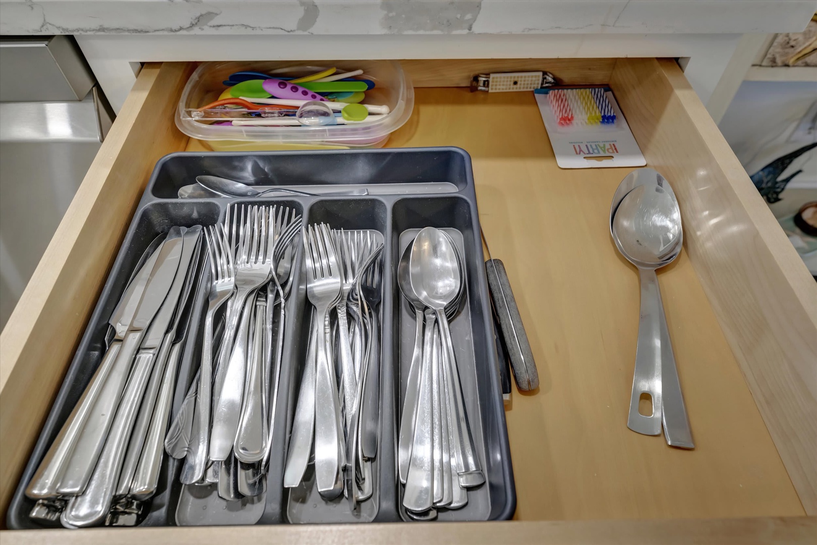 Open your kitchen drawer to find everything you need: stainless steel cutlery neatly organized, colorful measuring spoons, and cheerful straws ready for your morning smoothie.
