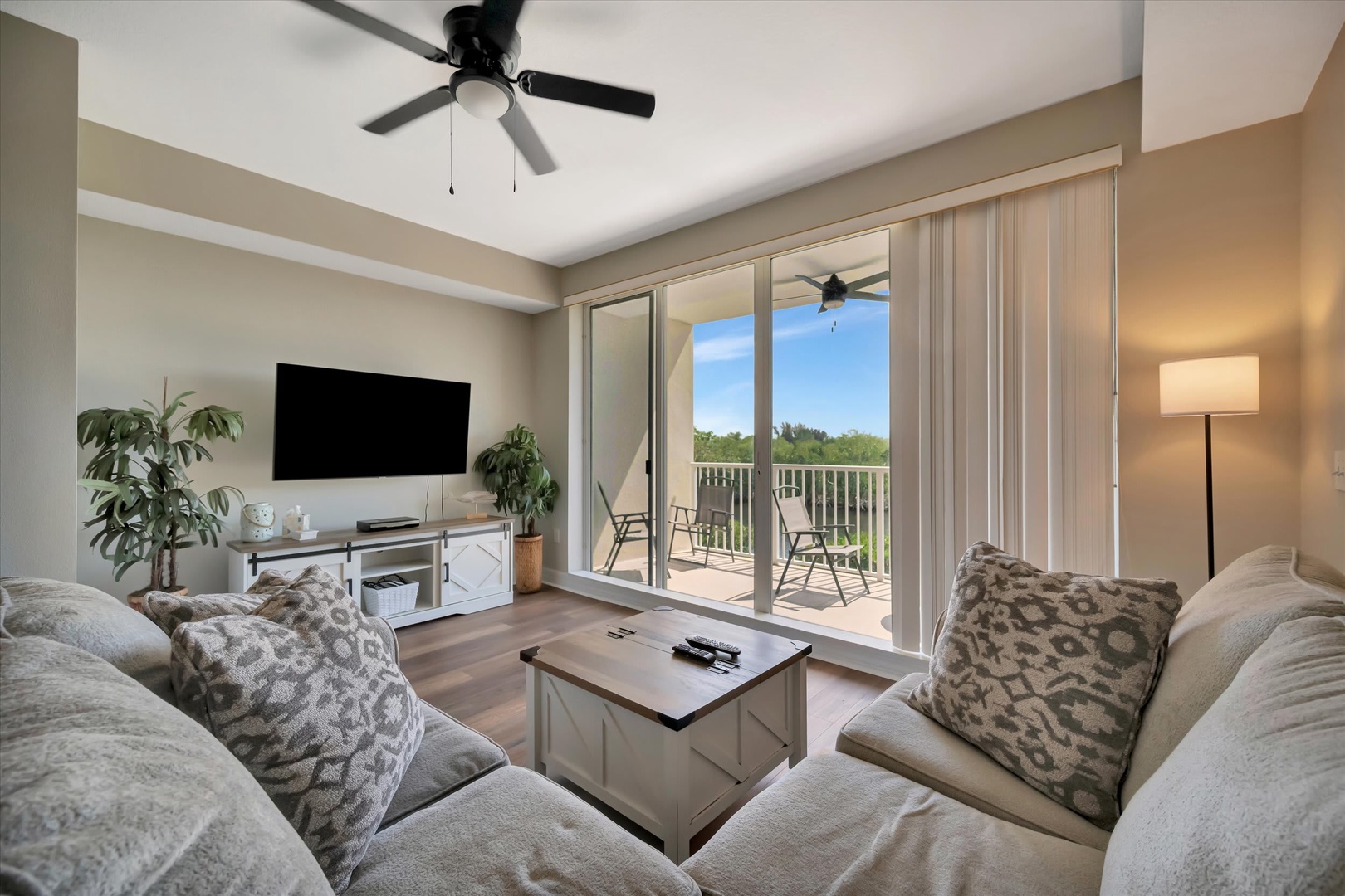 Settle into your bright, airy living space where plush seating invites you to unwind. Step through the glass doors to your private balcony and soak in peaceful views of lush greenery.