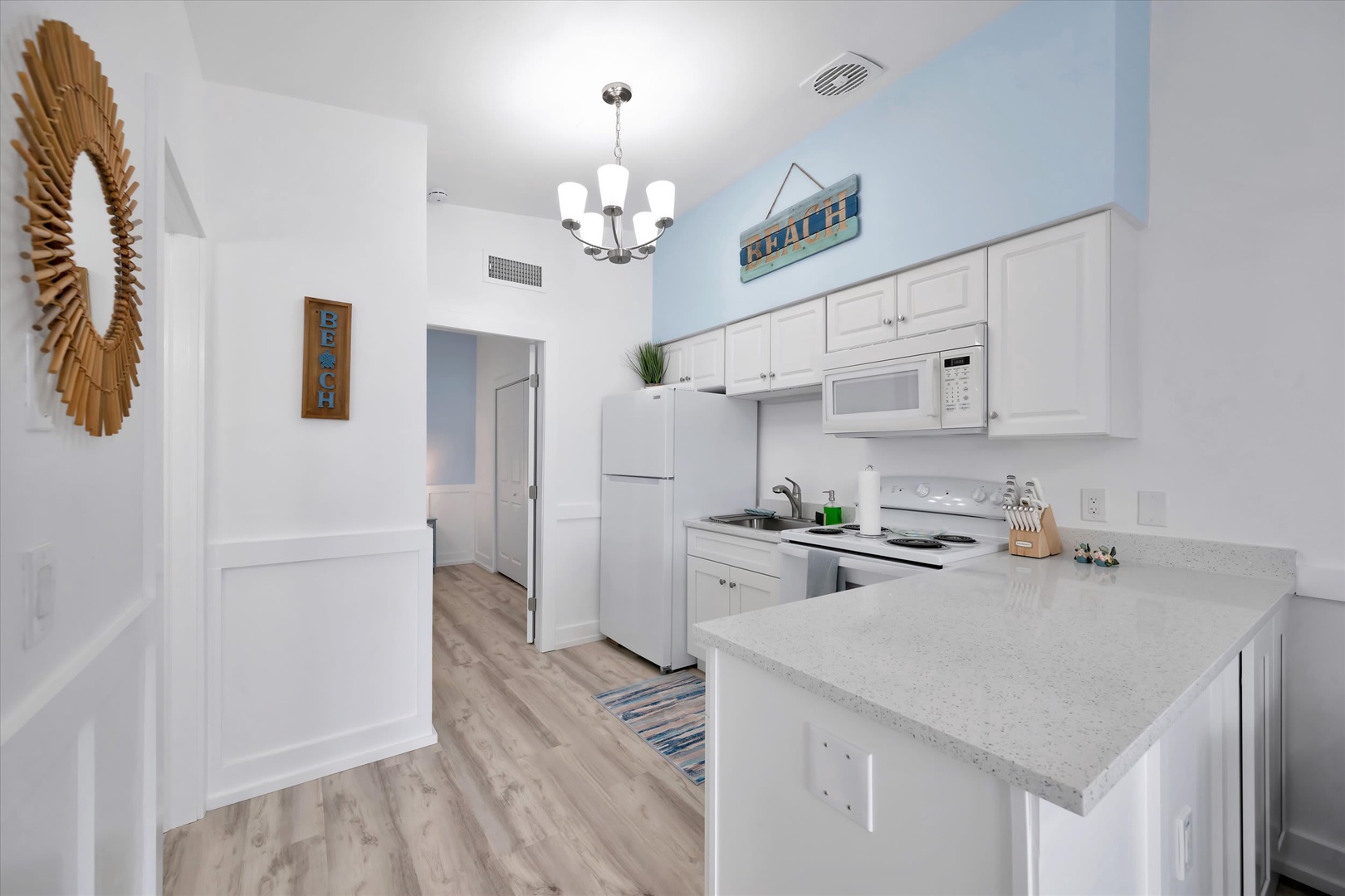 Step into your bright, beach-inspired kitchen with everything you need for a cozy stay. White cabinets and modern appliances make cooking a breeze, while coastal touches remind you that relaxation is just moments away.