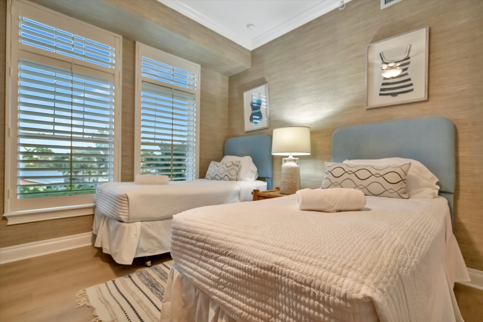 Two cozy beds await you in this serene guest room, dressed in crisp white linens and accented with modern décor. Natural light filters through plantation shutters, creating a peaceful retreat for restful nights.