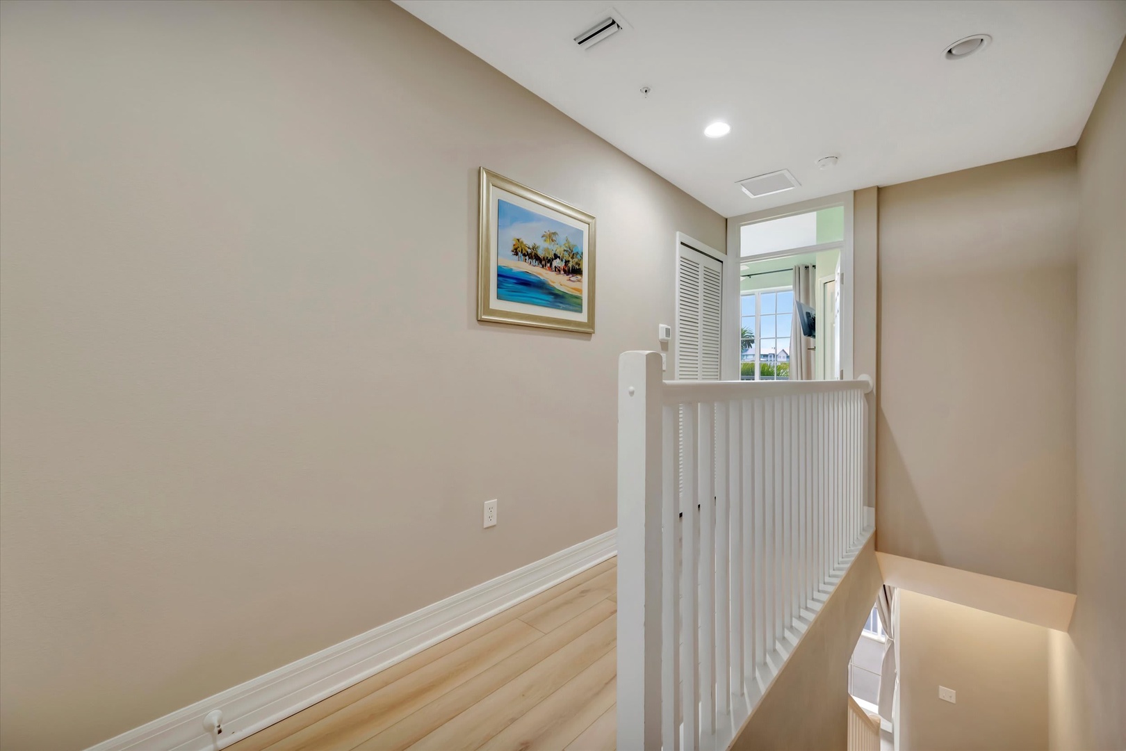 Light-filled hallway with clean lines and airy design. Natural light flows through the window ahead, creating a calm, welcoming space perfect for your beach getaway.