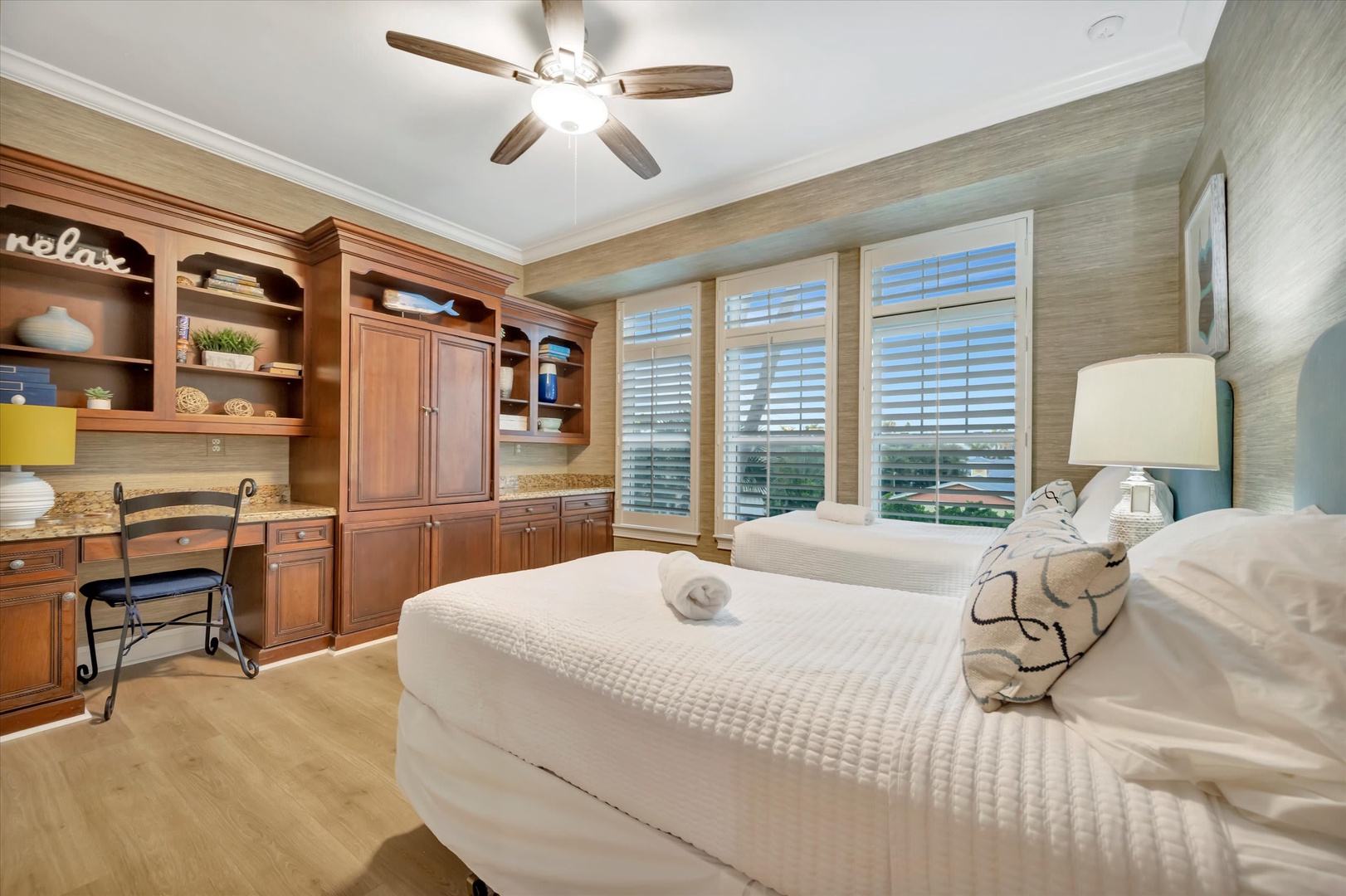Drift off to sleep beneath a gentle ceiling fan, with crisp linens and shuttered windows framing natural light. Built-in cabinetry and a cozy desk make your stay both comfortable and convenient.