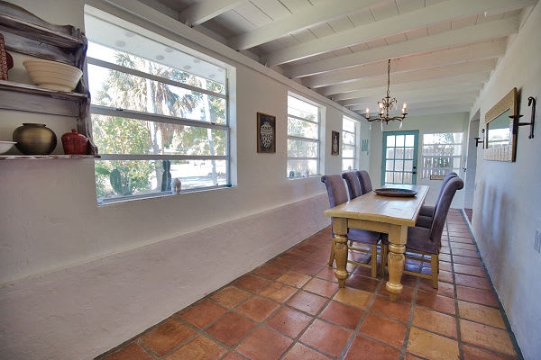 Gather around the handcrafted wooden table in your sunlit dining area, where rustic terracotta floors and charming ceiling beams create the perfect setting for memorable meals together.