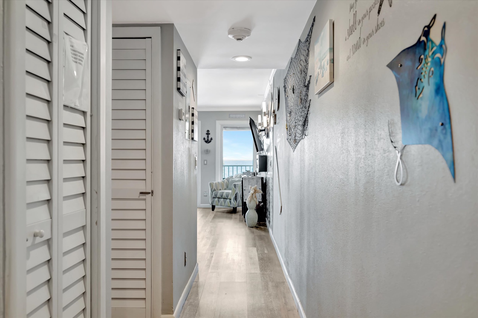 Your peaceful coastal hallway leads toward stunning ocean views, adorned with nautical touches and soft coastal hues that welcome you to your beachside retreat.