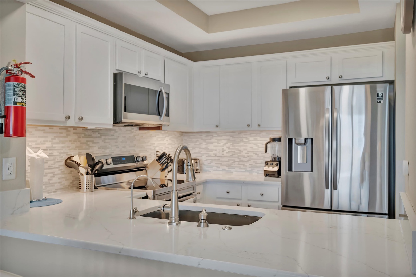 Step into your bright, fully equipped kitchen with sleek white cabinetry, gleaming countertops, and stainless steel appliances—everything you need to whip up your favorite meal or morning coffee in style.