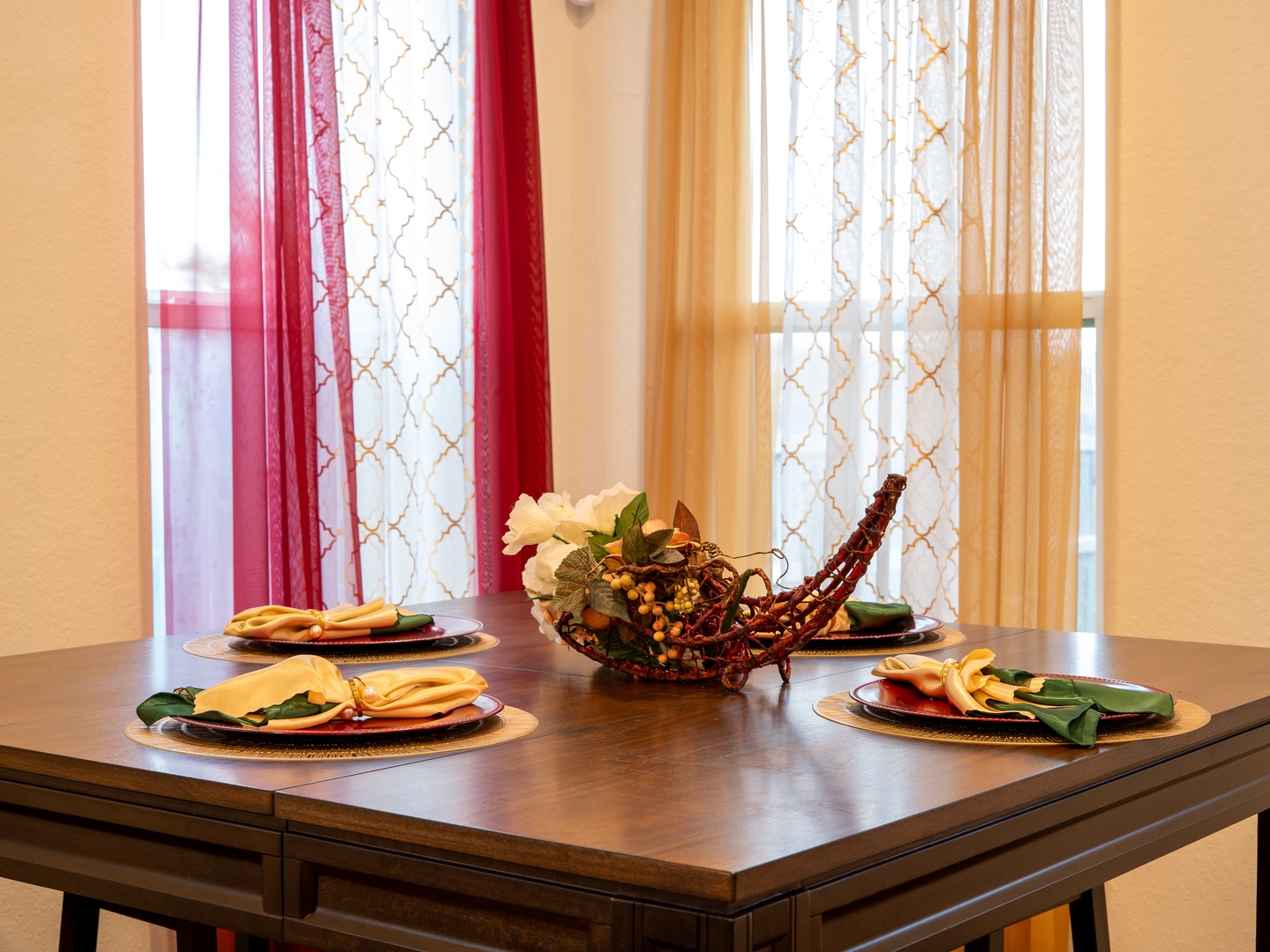 Gather around your welcoming dining table, elegantly set with colorful linens and a decorative centerpiece. Sunlight filters through sheer curtains, creating the perfect ambiance for meals and memories together.
