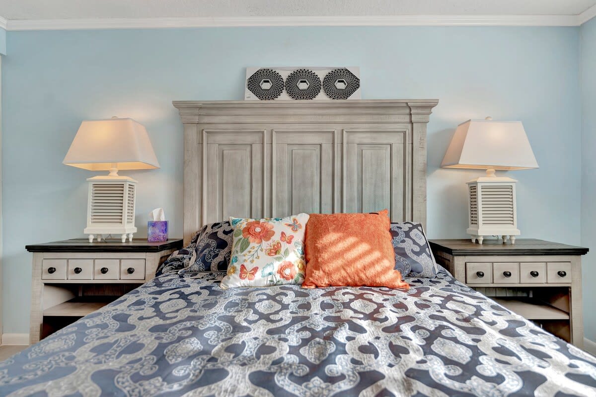 Sink into soft linens and restful coastal blues in your serene bedroom retreat. Twin lamps cast a warm glow as you unwind, surrounded by charming seaside-inspired decor that makes every evening feel like a getaway.
