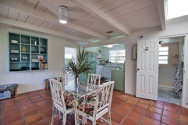Bright, open dining and kitchen with beachy charm. Whitewashed wood ceilings and terracotta tiles create a relaxed coastal atmosphere, perfect for gathering and cooking.