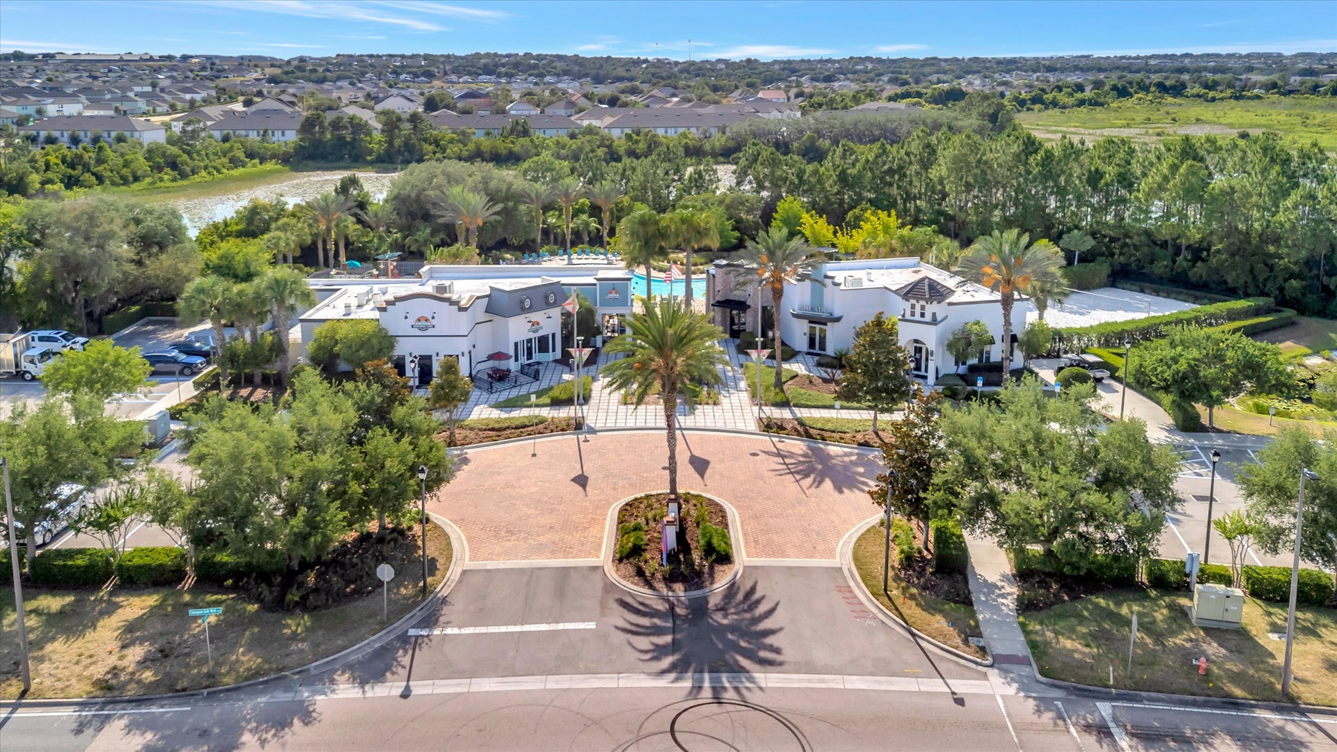 An elegant gated entrance welcomes guests to an exclusive vacation community surrounded by lush greenery, palm trees, and golf course views.