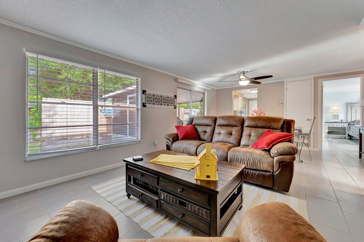 Unwind in your spacious living room with plush recliners and cool tile floors, where natural light and a ceiling fan create the perfect retreat for lazy afternoons.