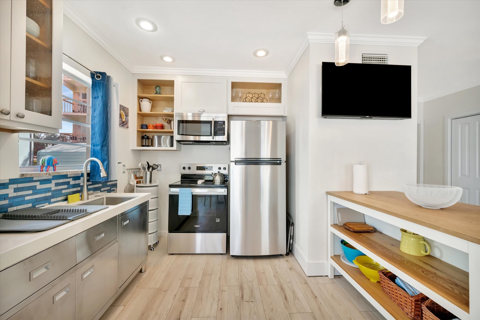 Step into your fully-equipped kitchen where stainless steel appliances and bright open shelving make meal prep a breeze. Natural light pours in while you enjoy the clean, modern design with coastal accents.