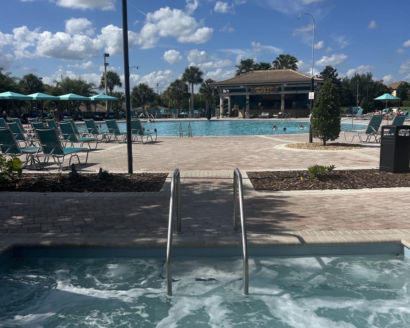 The resort-style pool complex features a hot tub, spacious sun deck with plenty of lounge chairs, and shaded pavilions—perfect for soaking up sunshine or relaxing poolside on your vacation.