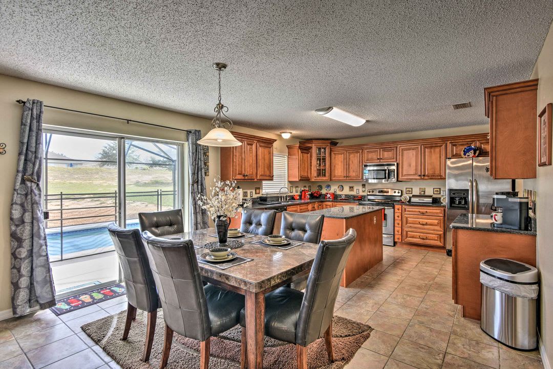 Gather around the spacious kitchen island with granite counters and rich wood cabinetry. Large sliding doors open to your outdoor space, filling the room with natural light and views of the open landscape beyond.