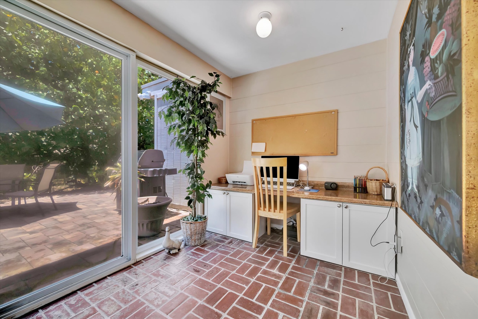 Step into your bright sunroom workspace with classic brick floors and glass doors opening to your private patio—perfect for morning coffee or working with a garden view.