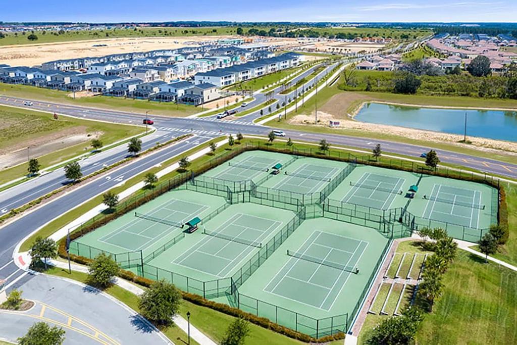 Aerial view of the community tennis courts and scenic pond, part of the resort's expansive recreational amenities spread across the surrounding development.