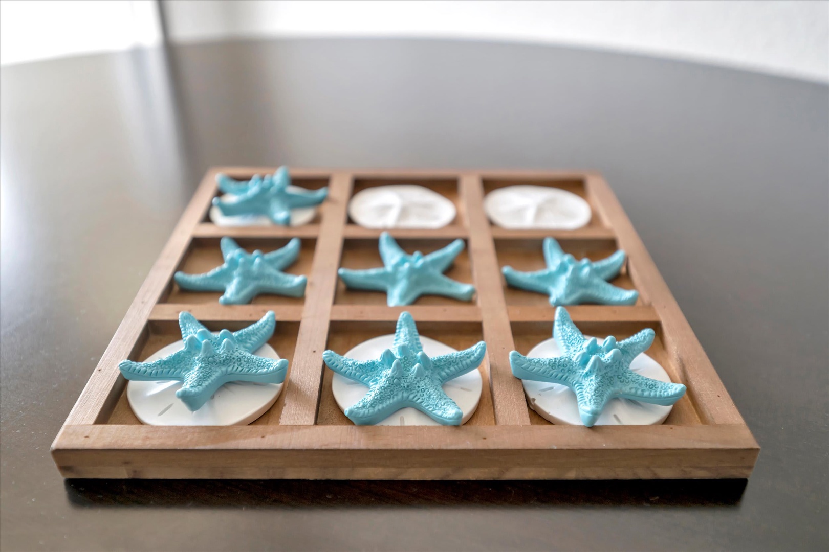 Challenge your travel companion to a beachside game of tic-tac-toe with charming starfish and shell pieces that capture the coastal spirit of your getaway.