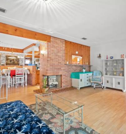 Bright, open living space with rich wood tones and charming brick fireplace. Comfortable seating and seamless flow between living, dining, and kitchen areas—perfect for your getaway.