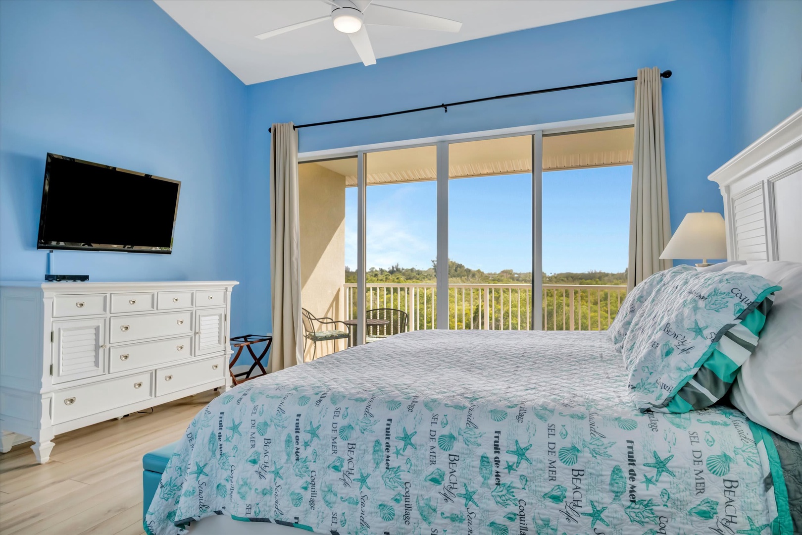 Wake up to serene views of lush natural landscape through your private balcony's floor-to-ceiling glass doors. The coastal-inspired bedroom offers a peaceful retreat with a ceiling fan and all the comforts you need.