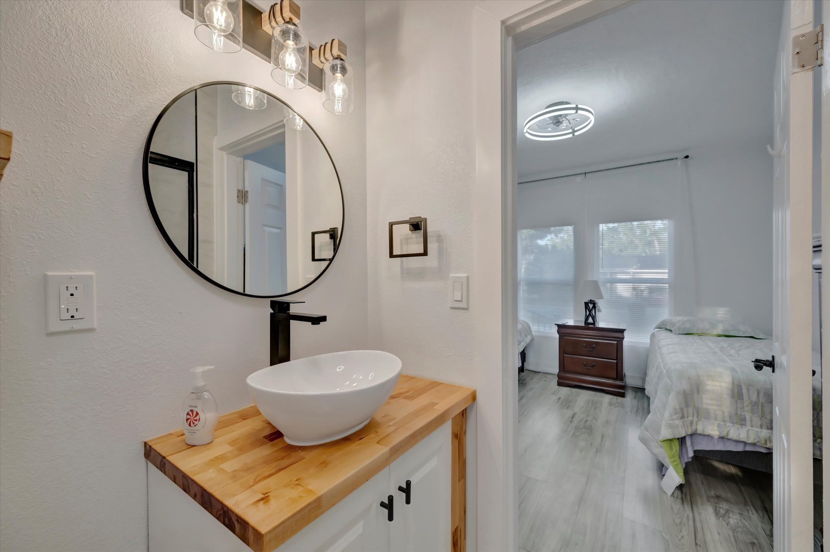 Refresh in your stylish bathroom with a modern vessel sink, warm wood vanity, and elegant round mirror—where every detail invites relaxation.