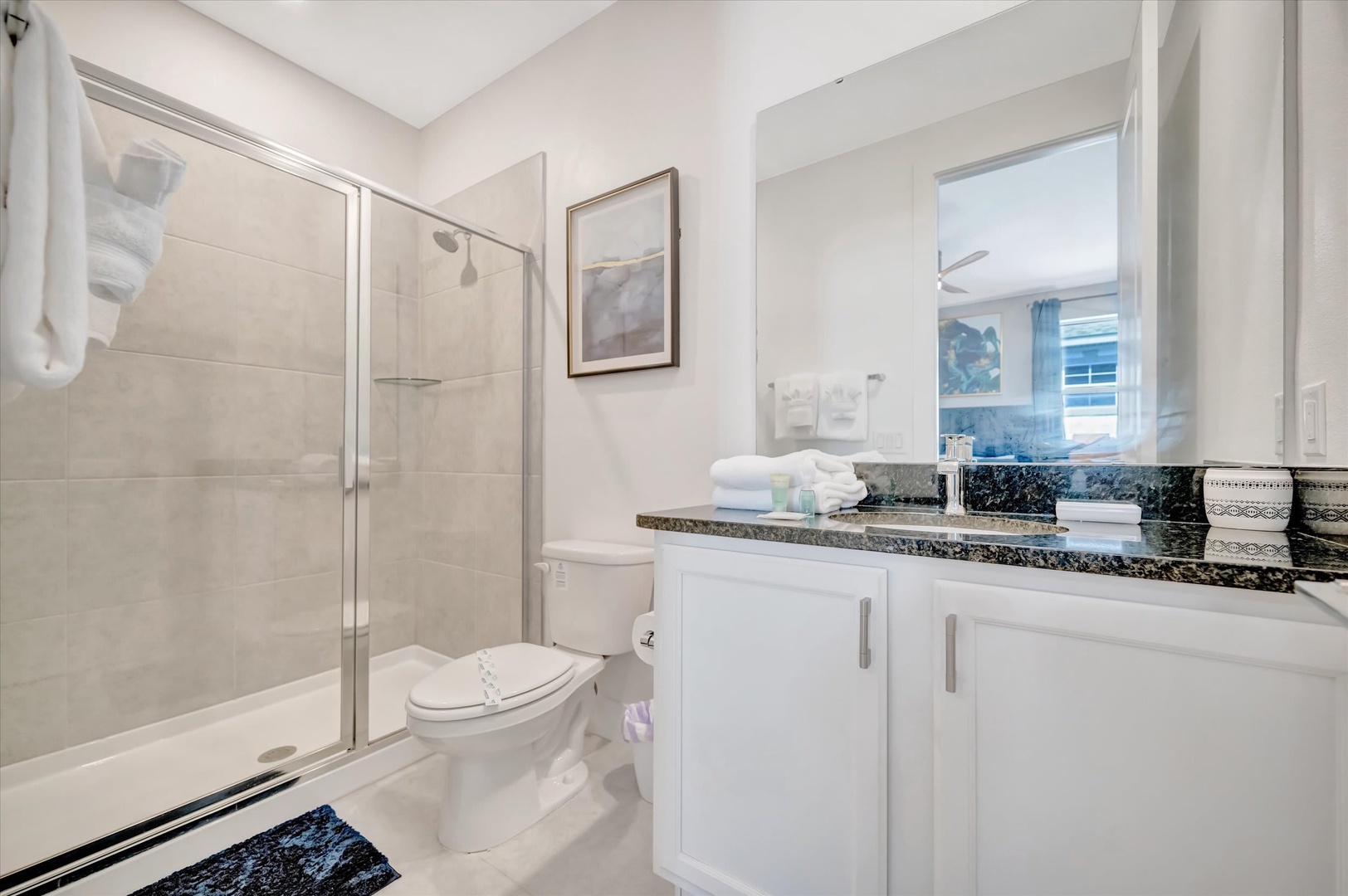 Refresh in your pristine bathroom with a spacious walk-in shower, granite vanity, and soft natural light streaming through the window. Plush towels and thoughtful details make every morning feel like a spa retreat.