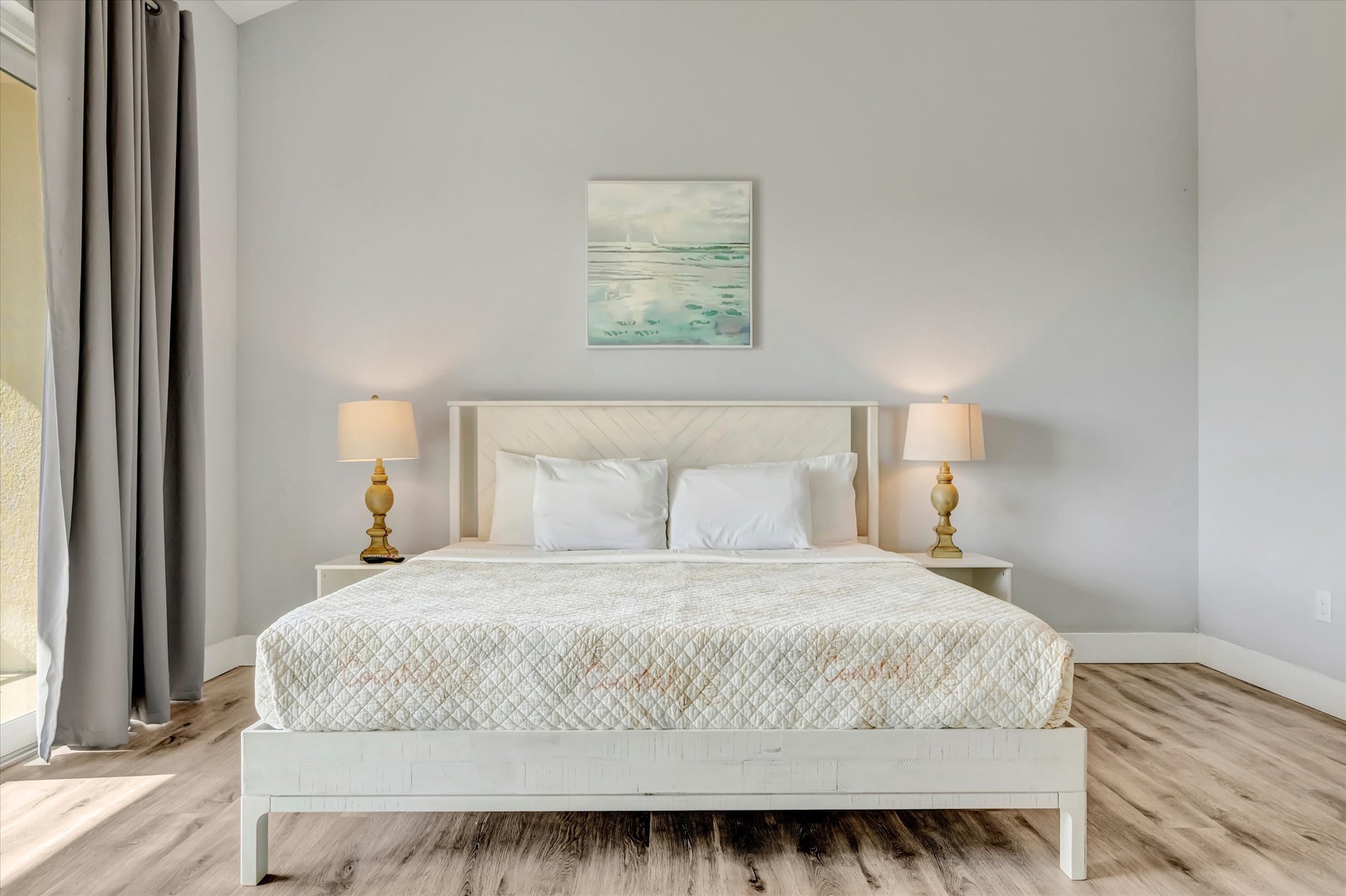 Your serene bedroom awaits with a plush bed dressed in soft linens, warm bedside lighting, and coastal touches that invite restful nights and refreshing mornings.
