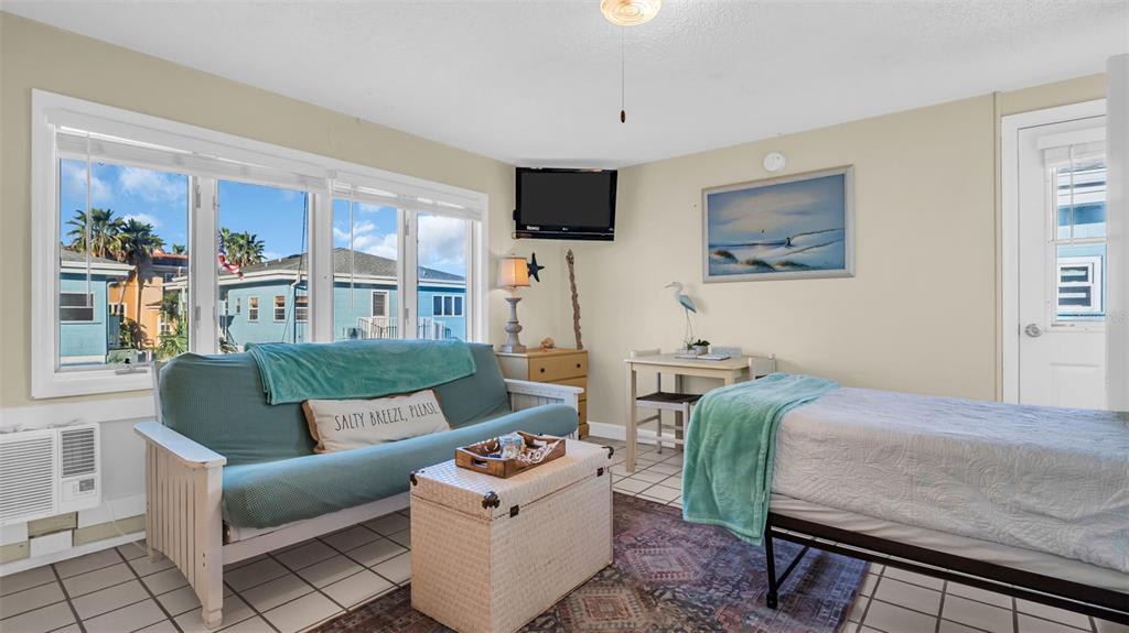 Relax in your bright, beach-themed retreat with coastal charm and sunny windows that frame colorful neighborhood views. The cozy sitting area and comfortable bed create the perfect space to unwind after a day of adventure.