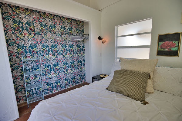 Settle into this serene retreat where vintage charm meets modern comfort. Your cozy bed awaits beneath soft natural light, with beautiful William Morris-inspired wallpaper creating a peaceful backdrop for restful nights.