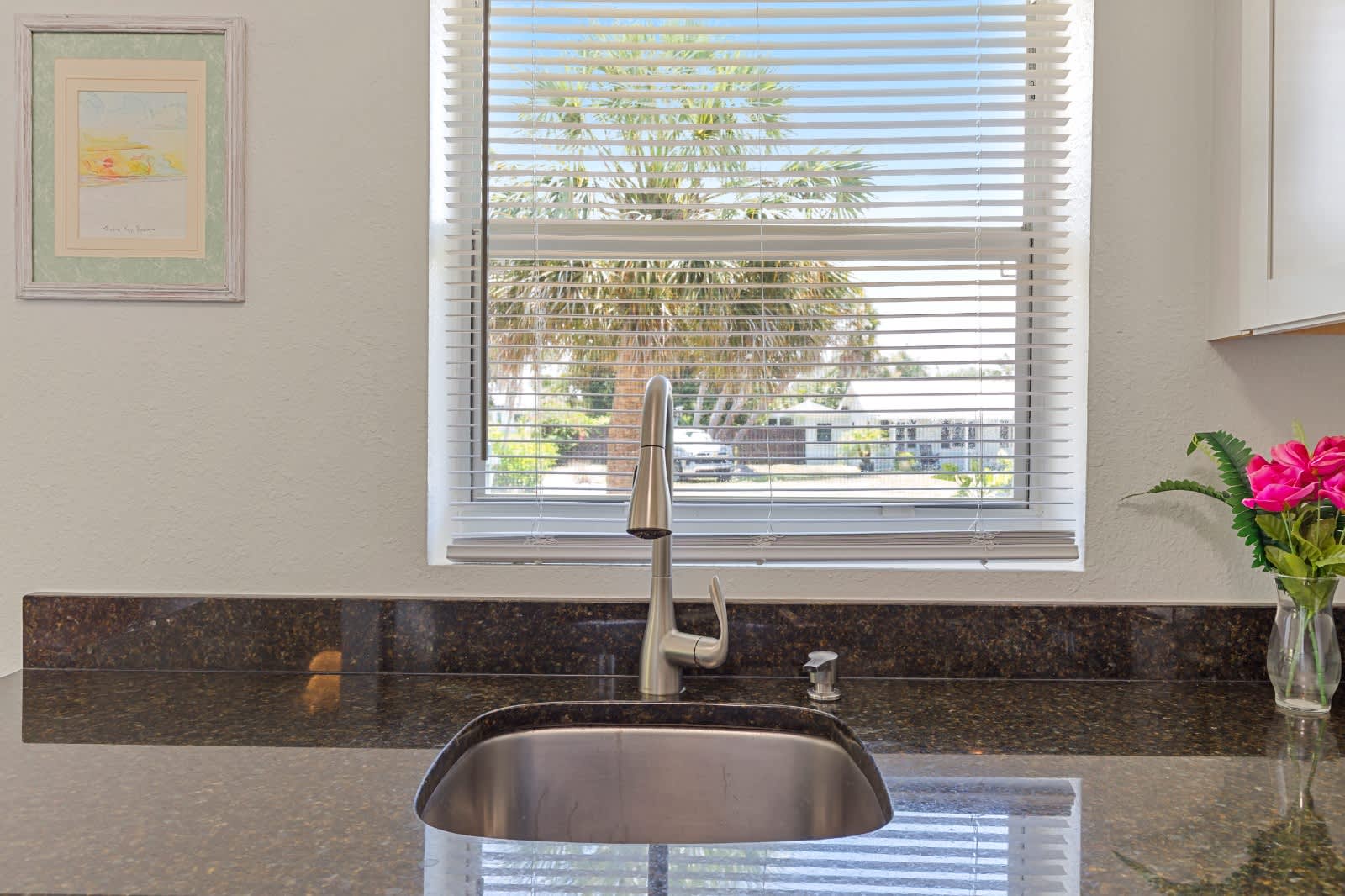 Sunlight streams through your kitchen window, offering a glimpse of the tropical palms outside while you prepare meals on polished granite counters. Fresh flowers add a welcoming touch to your private cooking space.