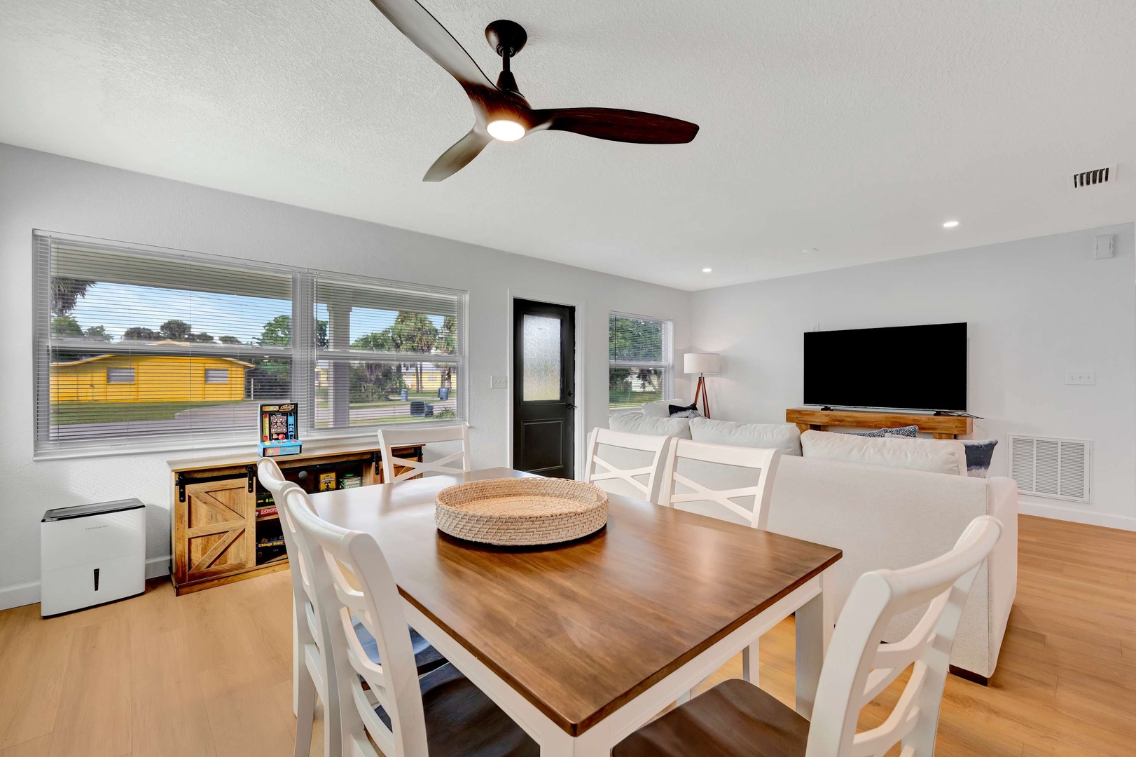 Your airy, open-plan living and dining area features warm wood floors, a ceiling fan overhead, and a cozy seating nook perfect for unwinding after a day of exploring.