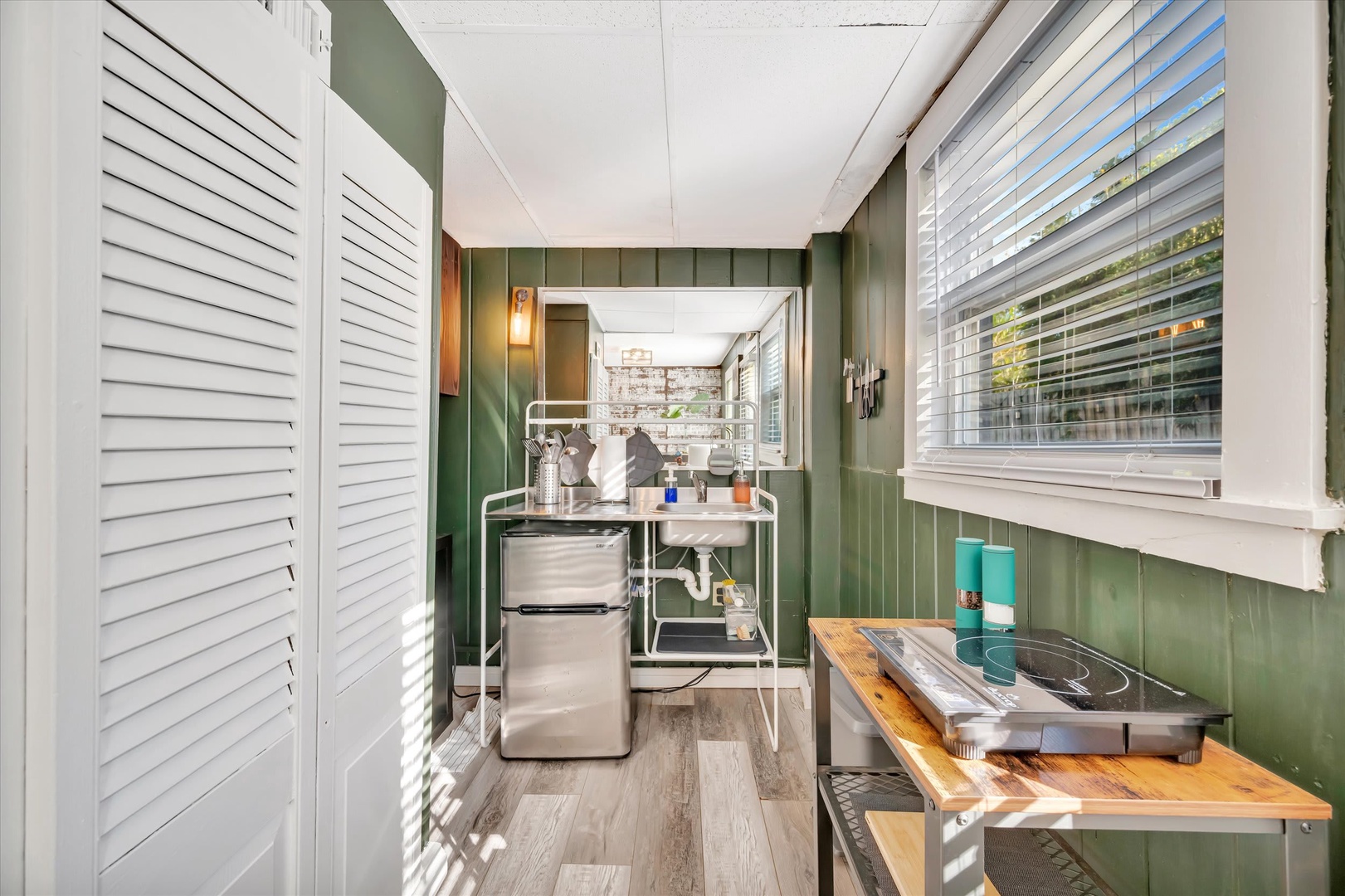 Sunlight pours into your cozy kitchenette, where rich green paneling and natural wood accents create a warm, cabin-like atmosphere. Everything you need for easy meal prep is right at your fingertips.
